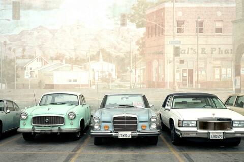 Verschiedene Oldtimer stehen nebeneinander auf einem Parkplatz.