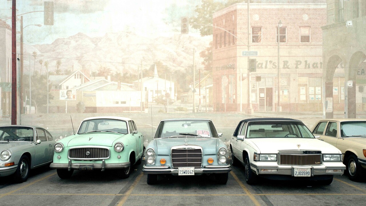 Verschiedene Oldtimer stehen nebeneinander auf einem Parkplatz.