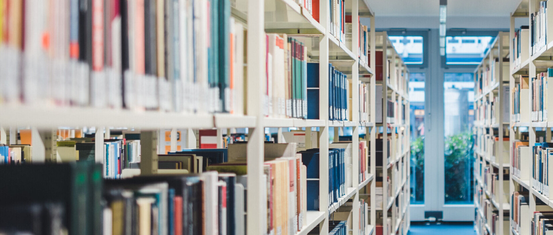 An aisle between two high bookshelves full of books in a library