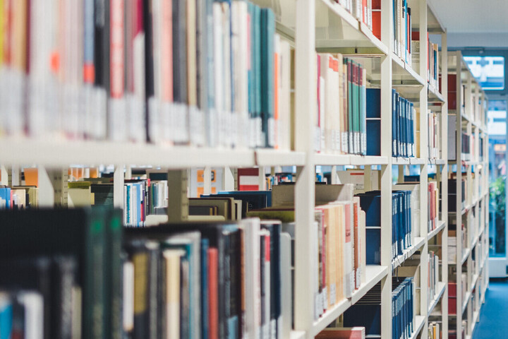 Ein Gang zwischen zwei hohen Bücherregalen voller Bücher in einer Bibliothek