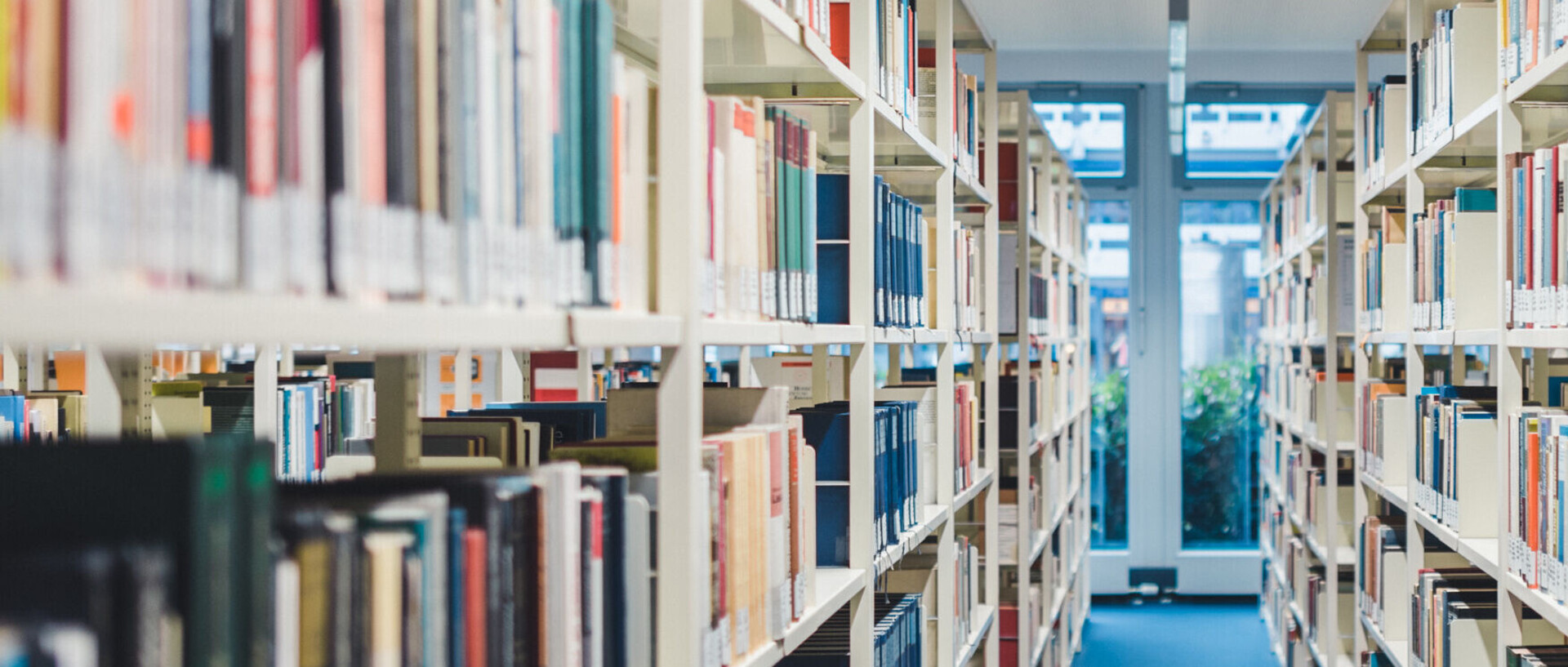 An aisle between two high bookshelves full of books in a library
