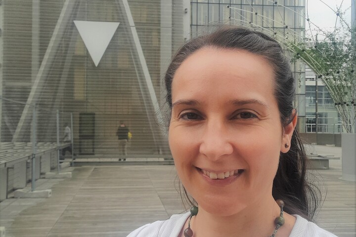 Porträt von Dr. Daniela Kuschel. Sie trägt ein weißes T-Shirt und ihre braunen Haare zu einem Zopf gebunden. Sie lacht offen in die Kamera. Link: Story Dr. Daniela Kuschel