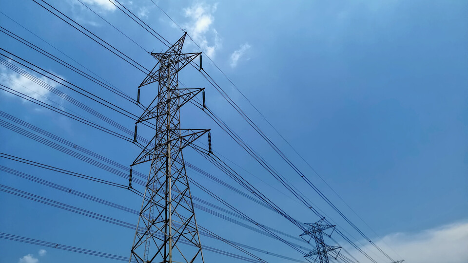 strommasten Zwei Strommasten mit gespannten Stromkabeln vor blauem Himmel