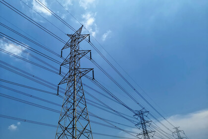 Zwei Strommasten mit gespannten Stromkabeln vor blauem Himmel