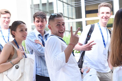 Fünf lächelnde Personen tragen schicke Kleidung und stehen nebeneinander. Alle tragen einen Lanyard der Universität LUIIS.