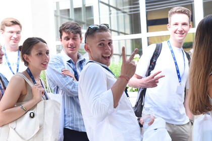 Fünf lächelnde Personen tragen schicke Kleidung und stehen nebeneinander. Alle tragen einen Lanyard der Universität LUIIS.