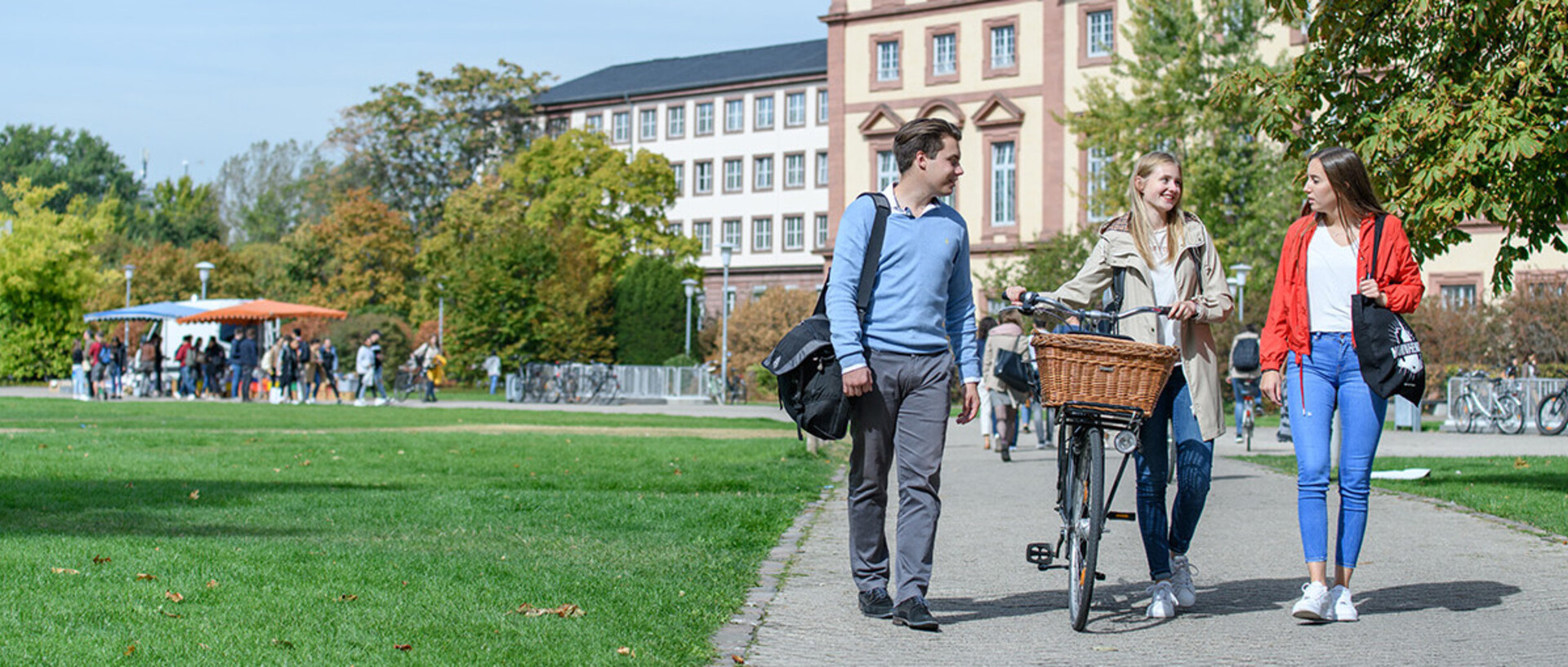 Drei Studierende laufen über die Neckarwiese