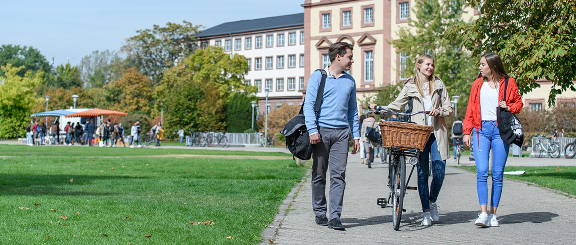 Drei Studierende laufen über die Neckarwiese