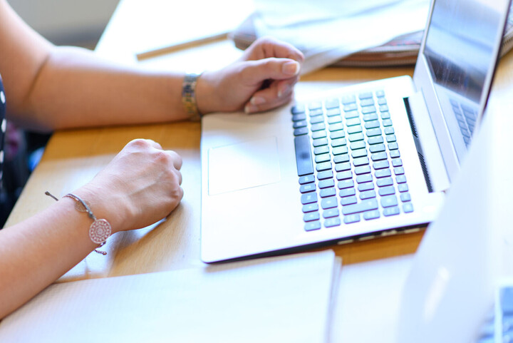 Woman working at a computer screen. Image detail shows hands and keyboard