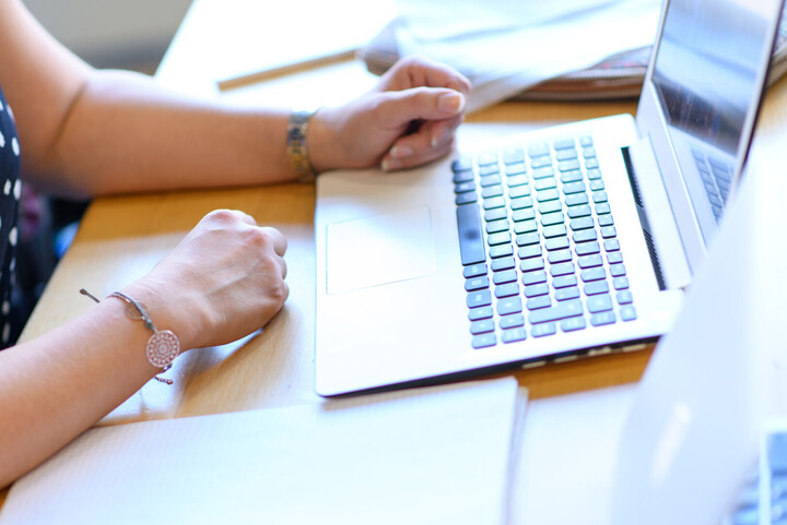 Frau, die am Bildschirm arbeitet. Ausschnitt zeigt Hände und Tastatur