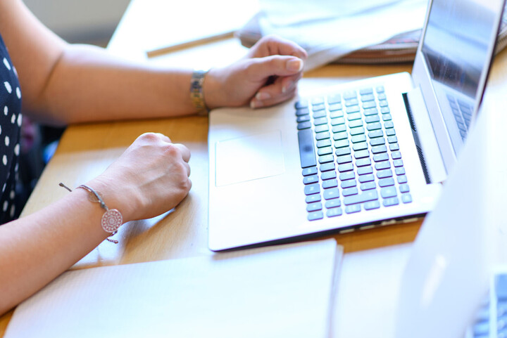 Frau, die am Bildschirm arbeitet. Ausschnitt zeigt Hände und Tastatur