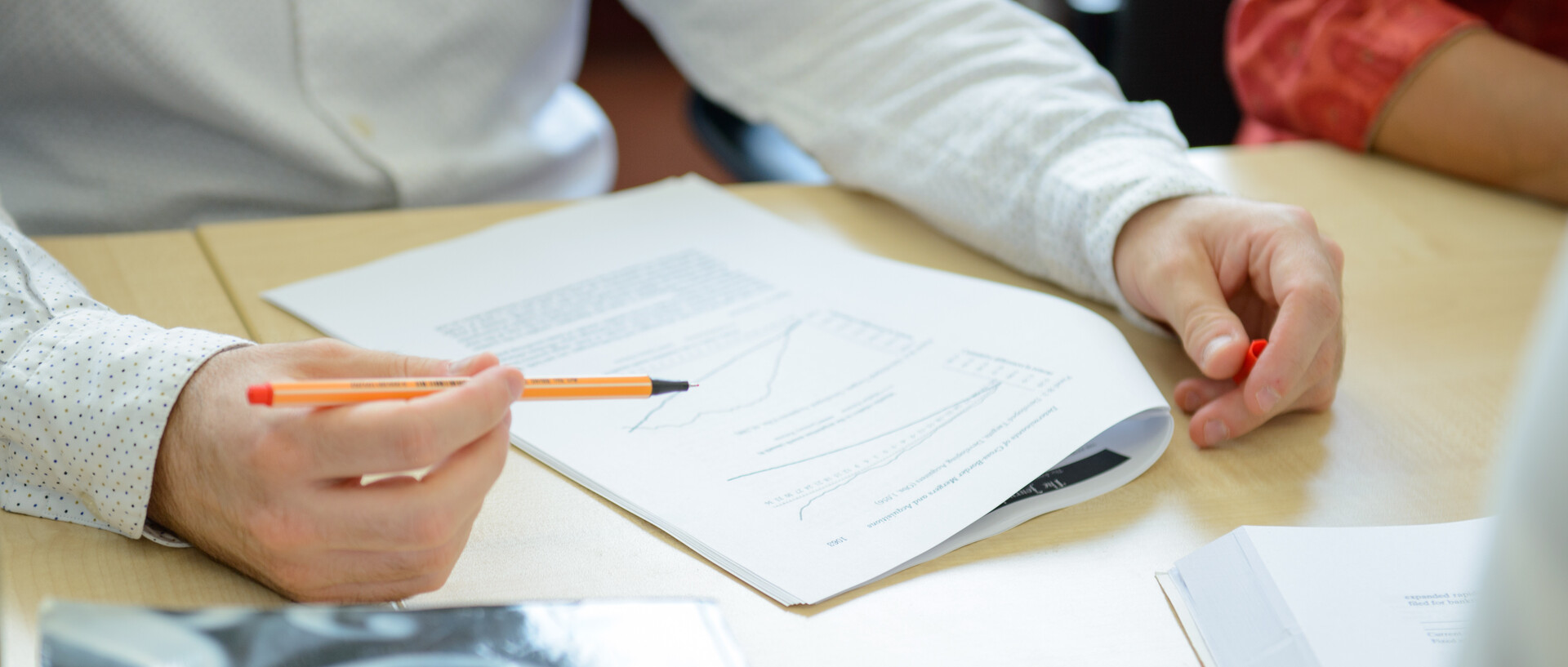 Hands of a person reading a text and marking passages with a pencil