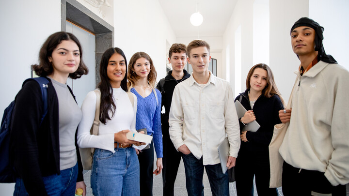 Eine Gruppe von Studierenden steht im Uniflur und schaut in die Kamera