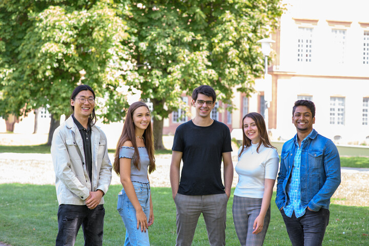 Eine Gruppe Studierender mit dem Mannheimer Schloss im Hintergrund