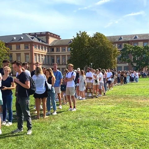 Studierende stehen in einer langen Schlange auf der Mensawiese. Im Hintergrund das Barockschloss Mannheim. Link: Instagram-Post Erstsemester