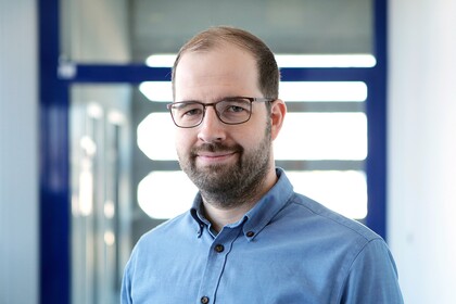 Lars Leszczensky. He is wearing a blue shirt and is standing inside the A5 building.