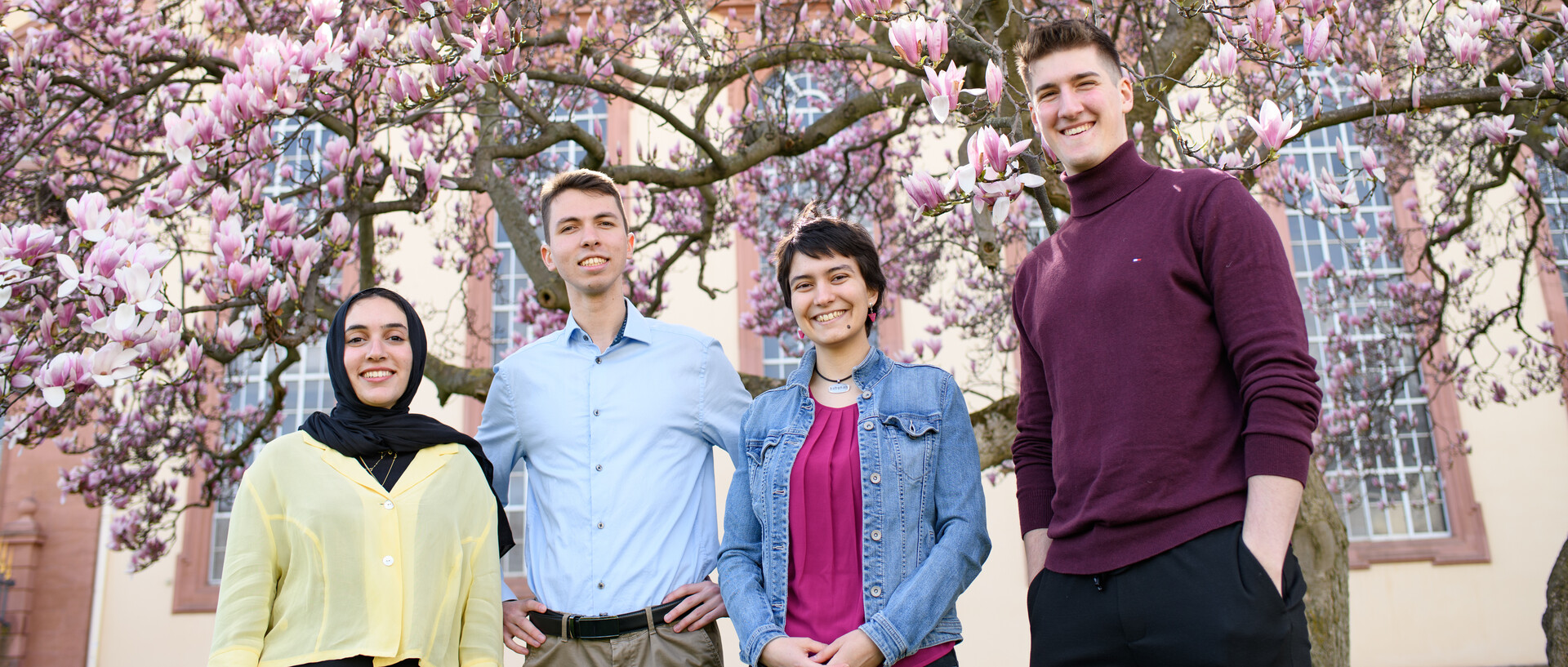 Eine Gruppe Studierende mit blühenden Magnolien im Hintergrund