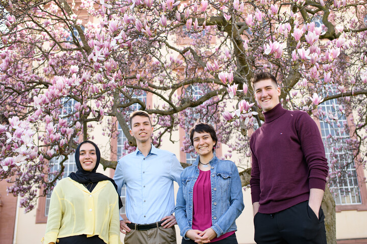 Eine Gruppe Studierende mit blühenden Magnolien im Hintergrund