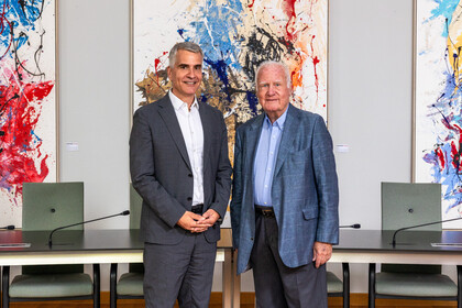 Rektor Thomas Fetzer und Manfred Fuchs posieren vor den Bildern von Fuchs.