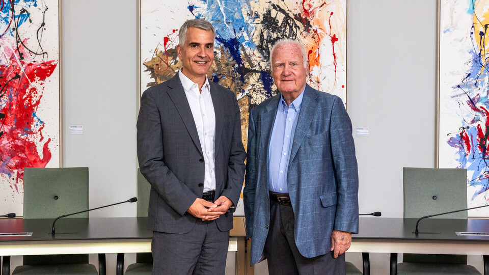 Rektor Thomas Fetzer und Manfred Fuchs posieren vor den Bildern von Fuchs.