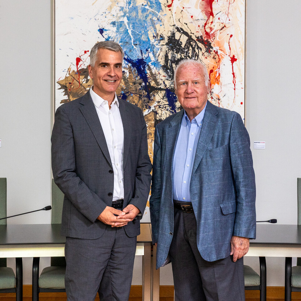 Rektor Thomas Fetzer und Manfred Fuchs posieren vor den Bildern von Fuchs.