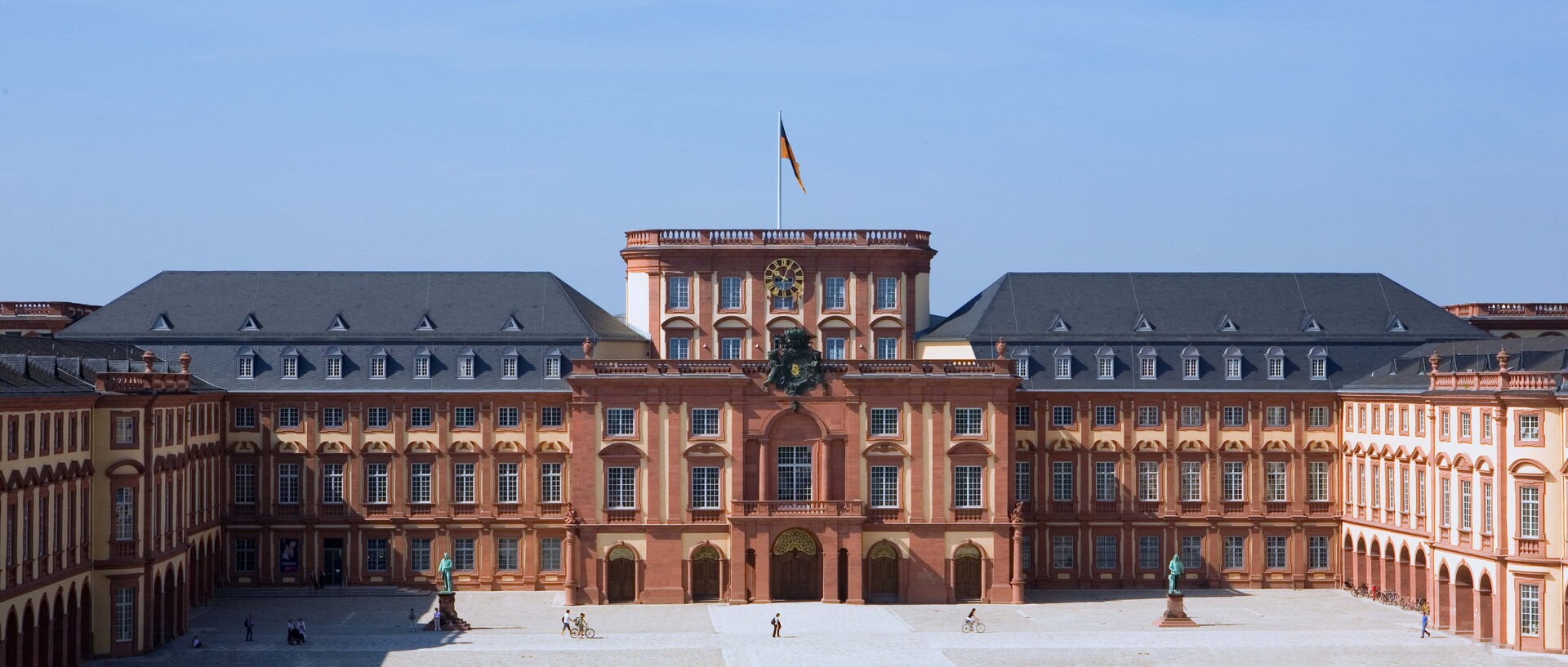 Mittelbau der Universität Mannheim an einem sonnigen Tag mit blauen Himmel.