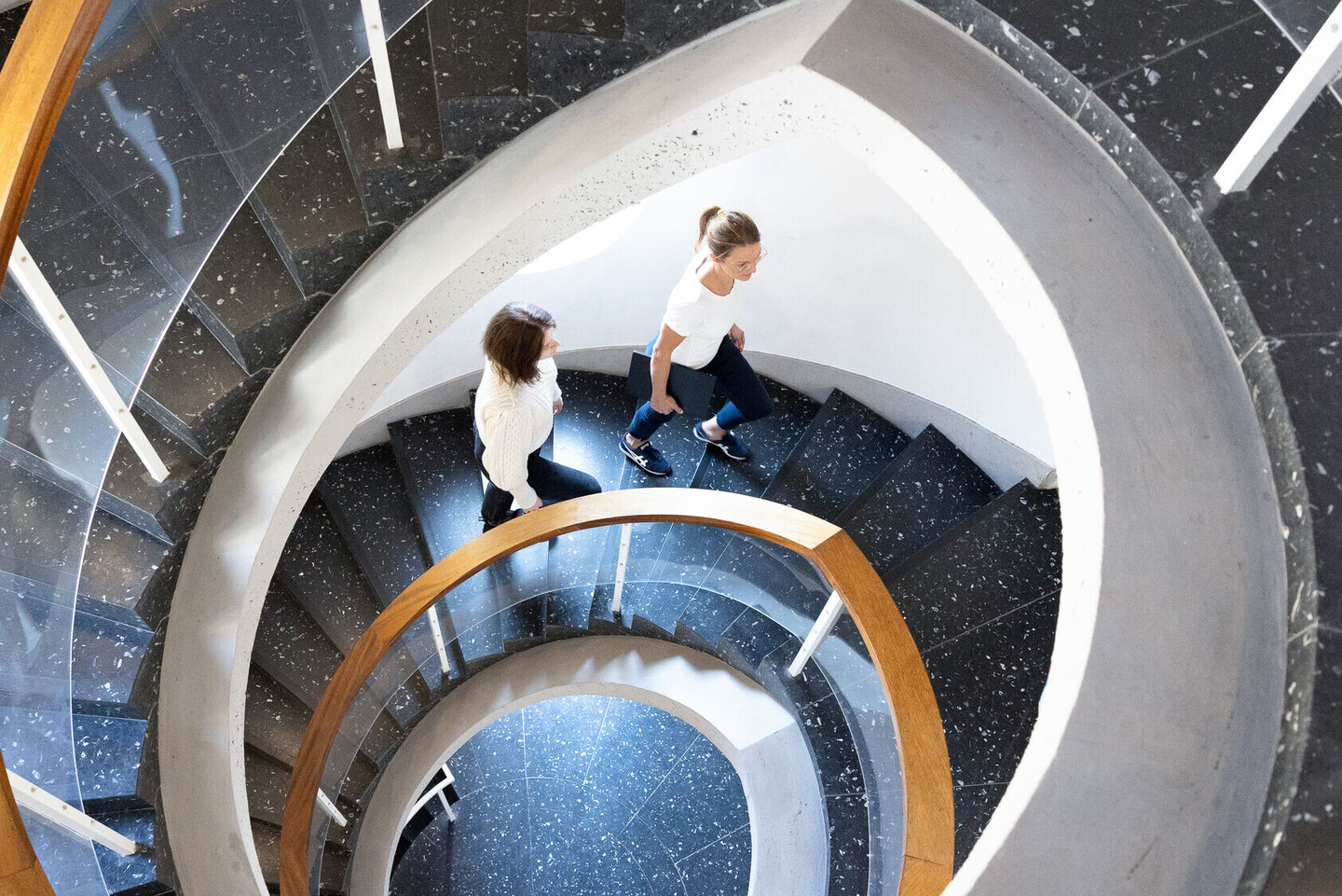 Ansicht von oben auf das Treppenhaus im Schneckenhofturm, 2 Frauen laufen die Treppe hoch. 