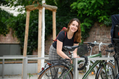 Eine Person schließt ihr Fahrrad an einem Fahrradständer ab. 