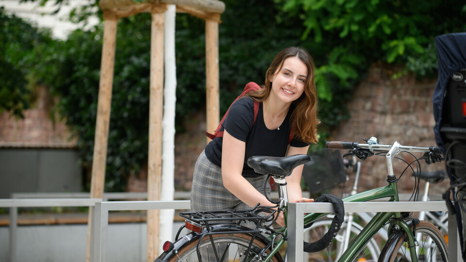 Eine Person schließt ihr Fahrrad an einem Fahrradständer ab.
