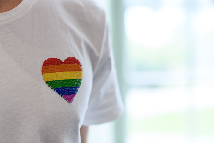 Auf einem T-Shirt ist ein Herz in Regenbogenfarben.