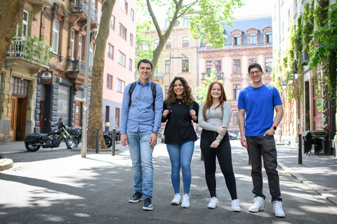 Four smiling students in a low-traffic zone in Mannheim’s Jungbusch district