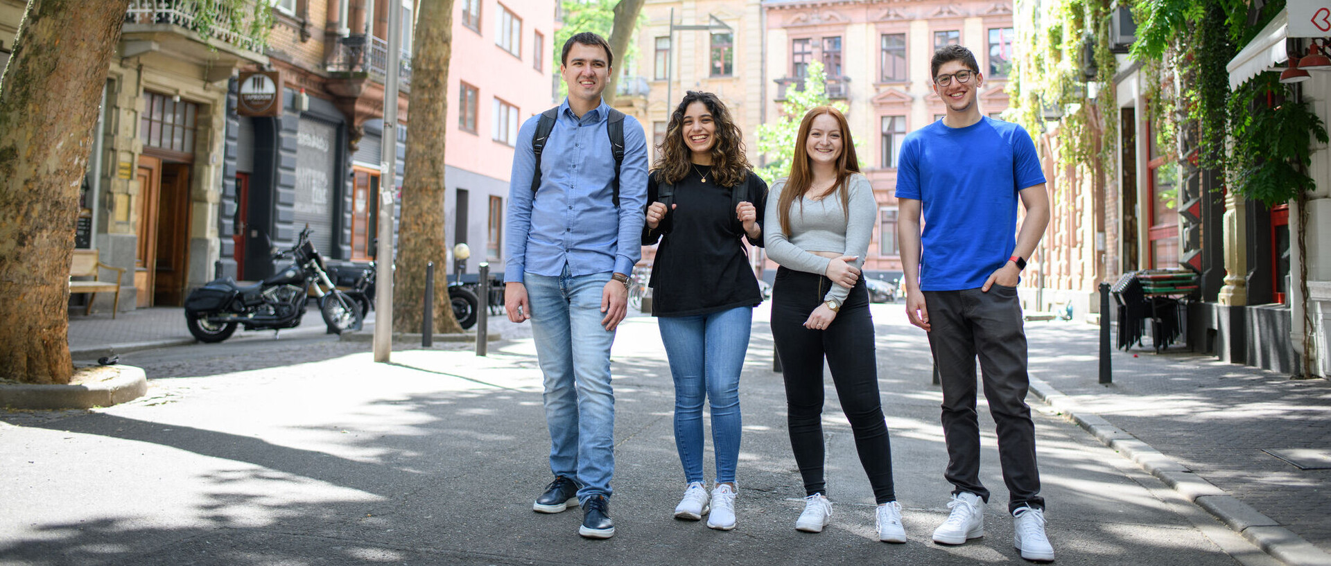 Four smiling students in a low-traffic zone in Mannheim’s Jungbusch district