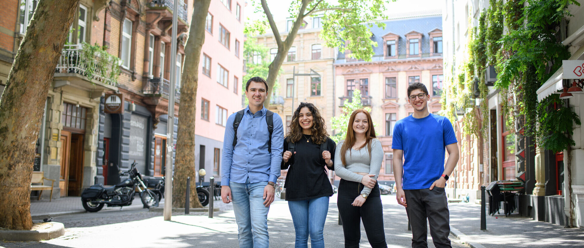 Four smiling students in a low-traffic zone in Mannheim’S Jungbusch district