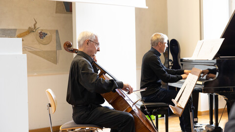 Professor Stefan Münzer sitzt an einem Flügel und Professor Manfred Hofer spielt Cello.