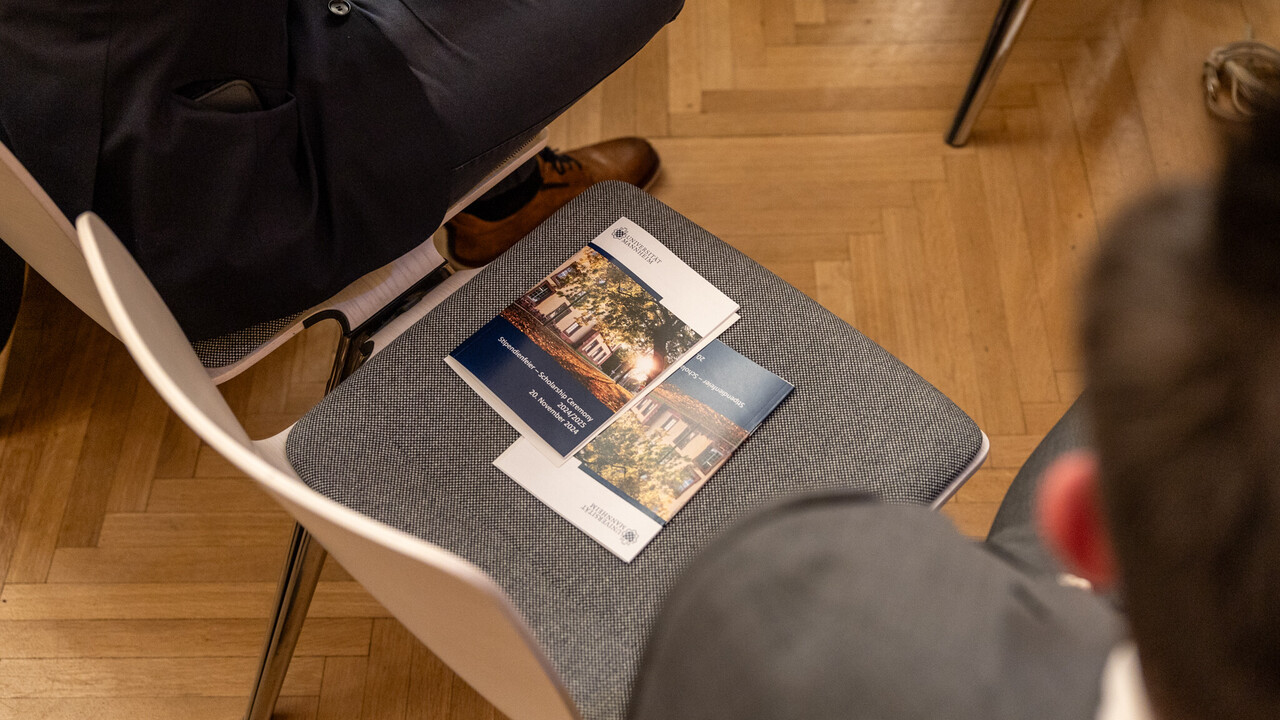Zwei Broschüren der Stipendienfeier liegen auf einem Stuhl