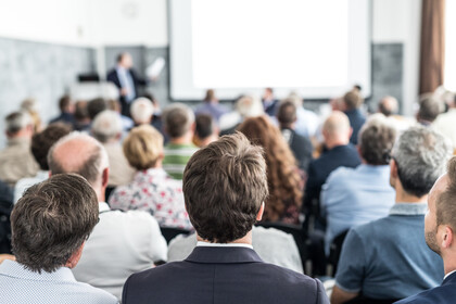 Redner hält einen Vortrag im Konferenzsaal bei einer geschäftlichen Veranstaltung. Publikum im Konferenzsaal. Konzept für Wirtschaft und Unternehmertum. Fokus auf unerkennbare Menschen im Publikum