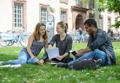 Studierende auf einer Wiese vor dem Schloss