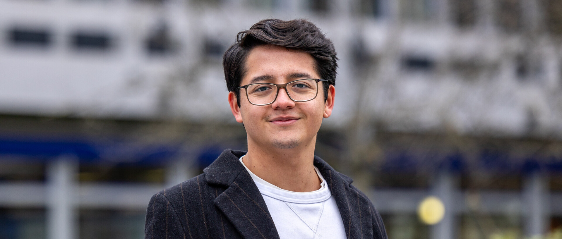Portraitfoto von Andrés Davila. Er trägt ein weißes T-Shirt und ein schwarzes Sakko.