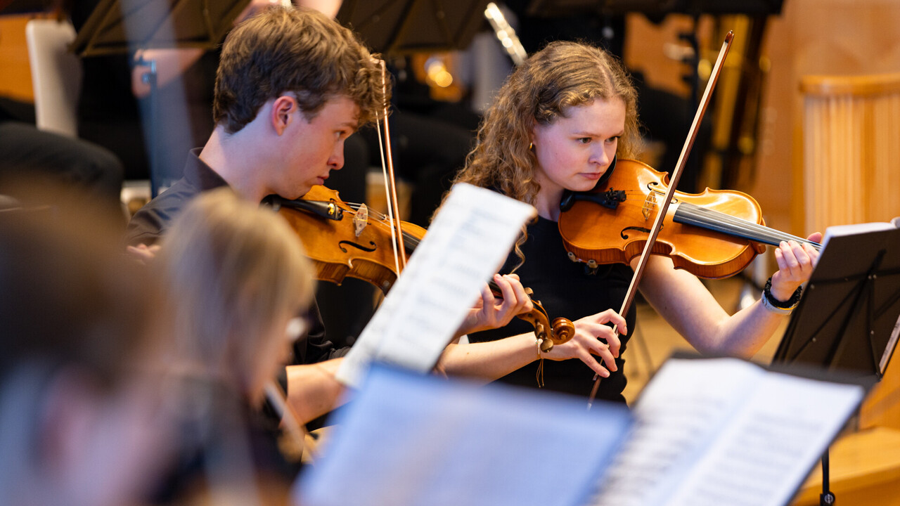 Auftritt des Uniorchesters. Studierende sind schwarz gekleidet und spielen jeweils ein Instrument.