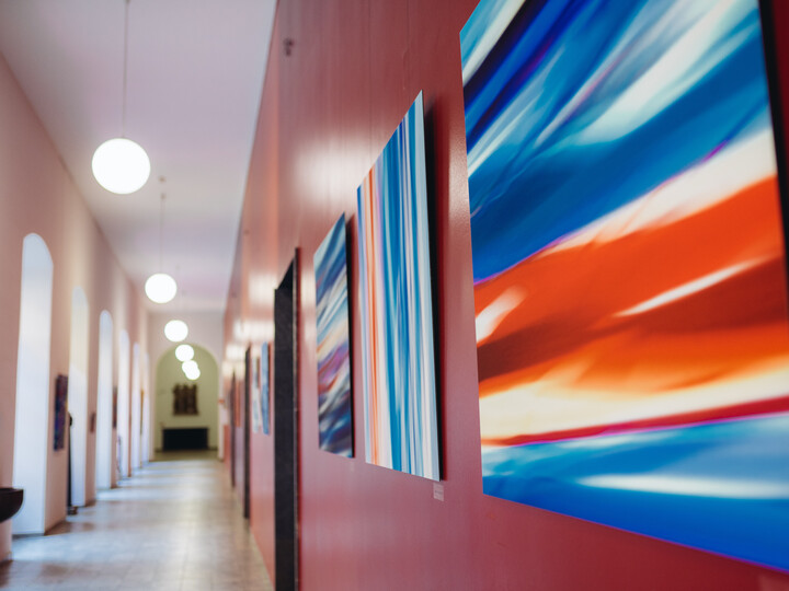 Flur des Rektorats im Ostflügel. An der roten Wand hängen verschiedene Kunstwerke in rot und blau.