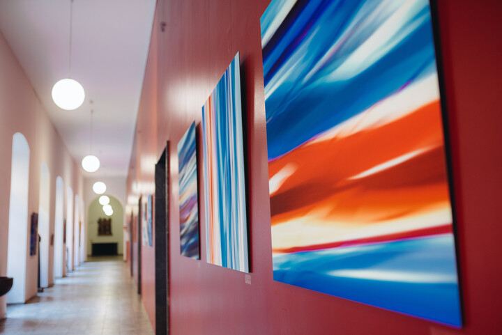 Flur des Rektorats im Ostflügel. An der roten Wand hängen verschiedene Kunstwerke in rot und blau.