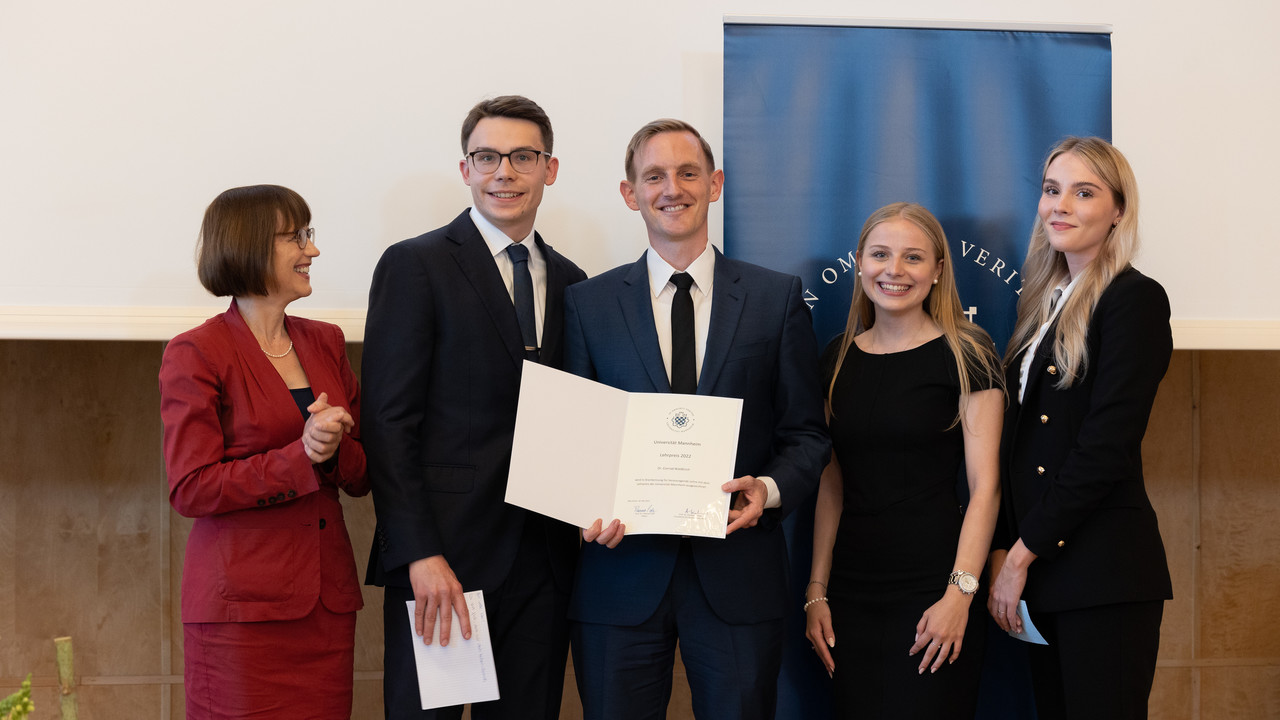 Gruppenbild mit Prof. Dr. Annette Kehnel und Dr. Conrad Waldkirch. Er hält eine Urkunde für den Lehrpreis 2022 in den Händen.