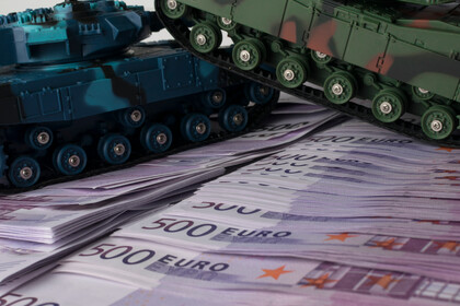 Zwei Spielzeugpanzer auf gestapelten 500-Euro-Scheinen.