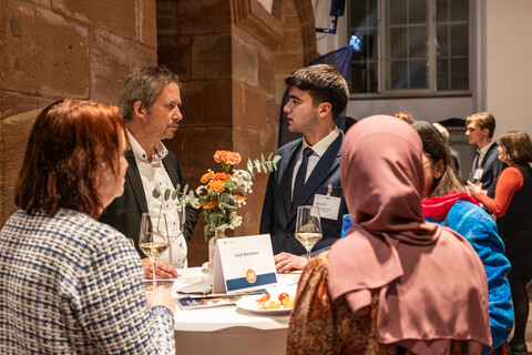 Fünf Personen unterhalten sich an einem Tisch 