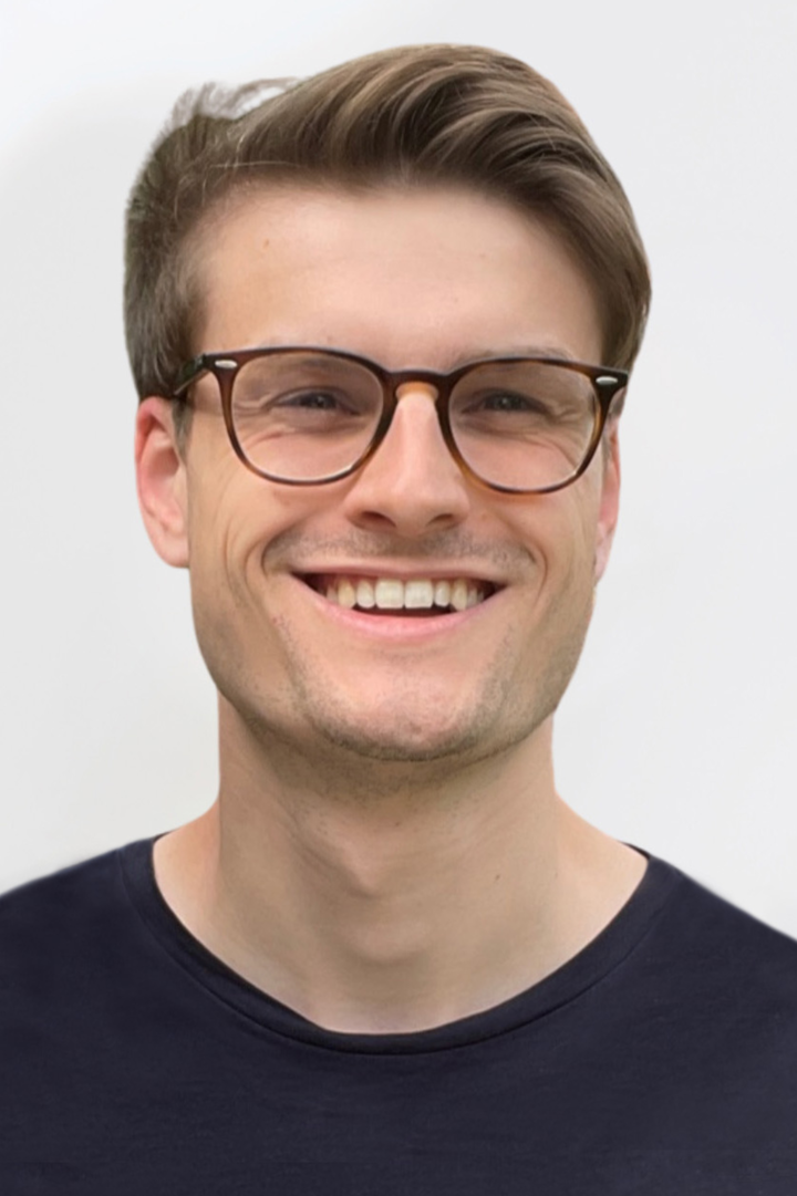 Porträt von Ulrich Roschitsch. Er trägt einen dunklen Pullover, hat braune, kurze Haare und eine Brille.