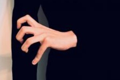 Eine Person mit schwarzem Oberteil krallt ihre linken Finger in ihren rechten Arm.