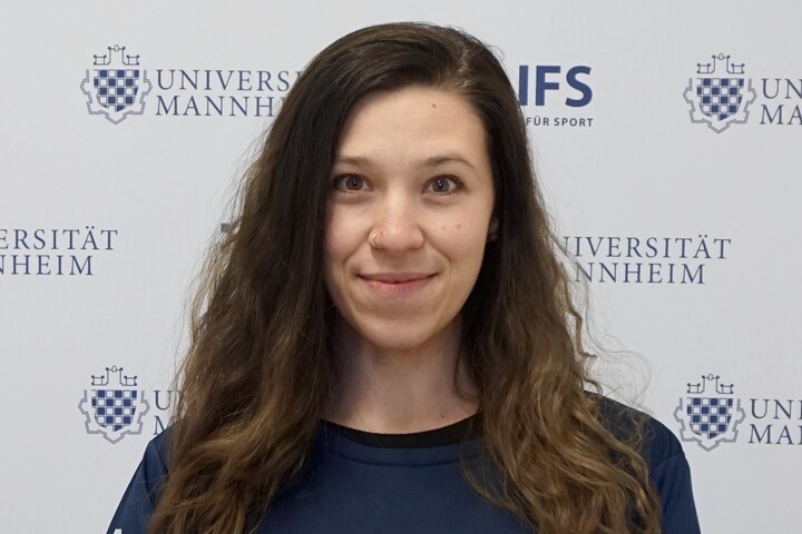 Charlotte Werner hat lange braune Haare. Sie trägt ein dunkelblaues Oberteil mit der Aufschrift "Universität Mannheim".