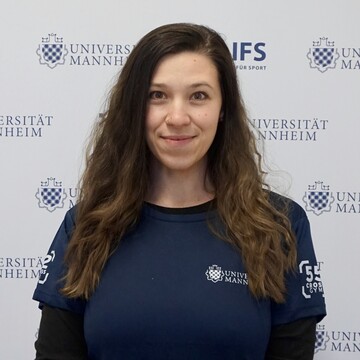 Charlotte Werner hat lange braune Haare. Sie trägt ein dunkelblaues Oberteil mit der Aufschrift "Universität Mannheim".