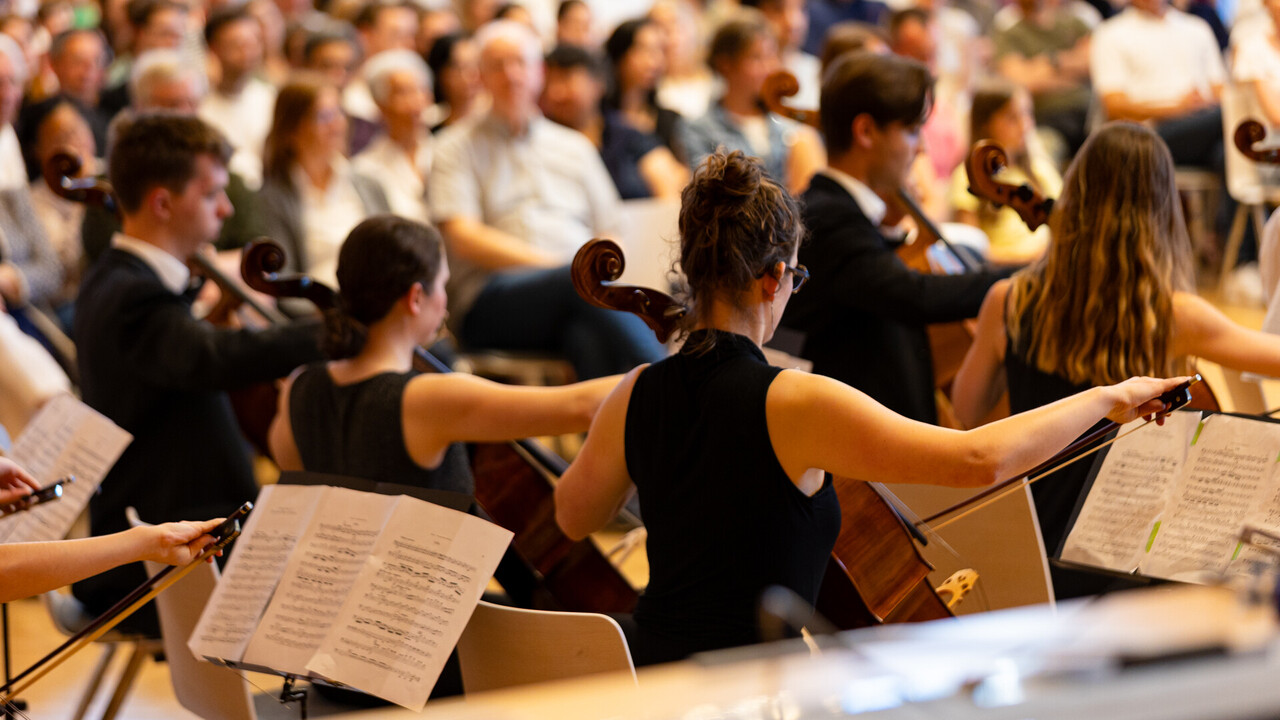 Auftritt des Uniorchesters. Studierende sind schwarz gekleidet und spielen jeweils ein Instrument
