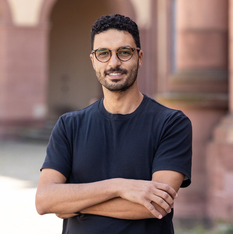 Portraitfoto von Hossam Abdellatif. Er trägt eine Brille und ein dunkelblaues T-Shirt.